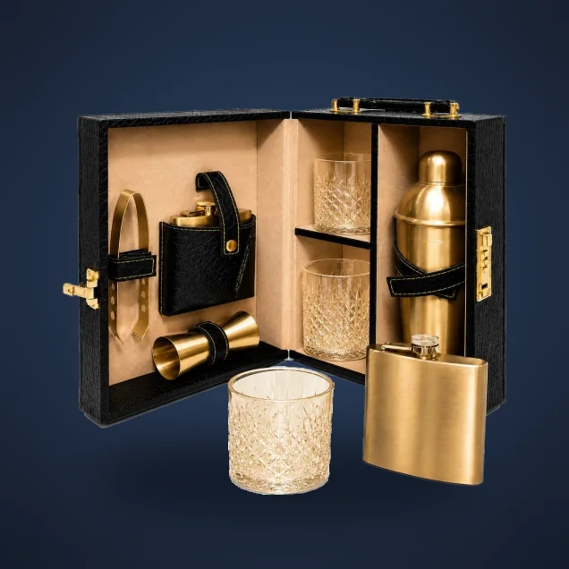 Open black portable bar case with gold shaker, flask, jiggers and two crystal glasses